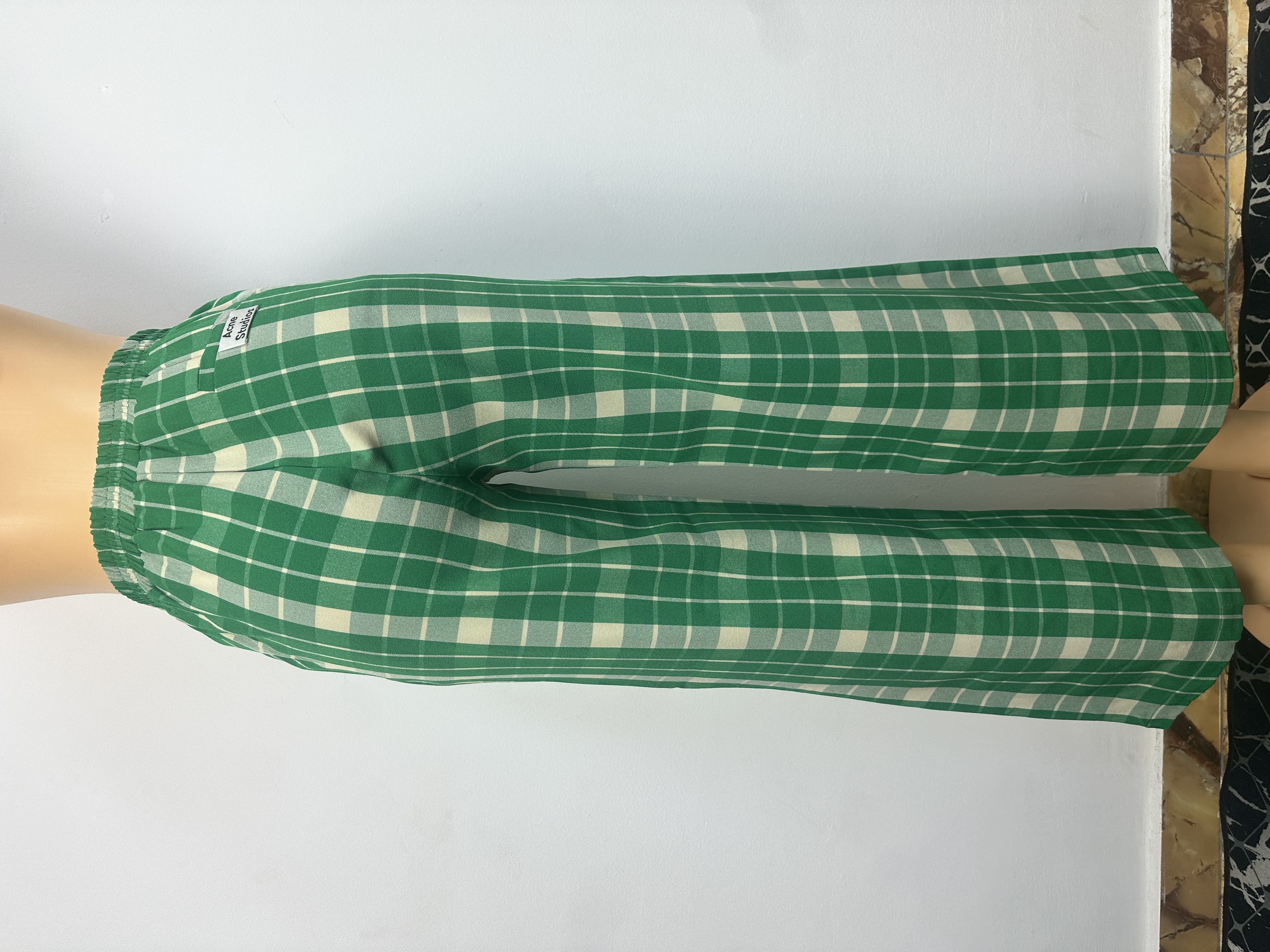 Pantalon vert, à carreaux blancs, il est doté d'une ceinture élastique et ne présente ni boutons ni cordons de serrage.