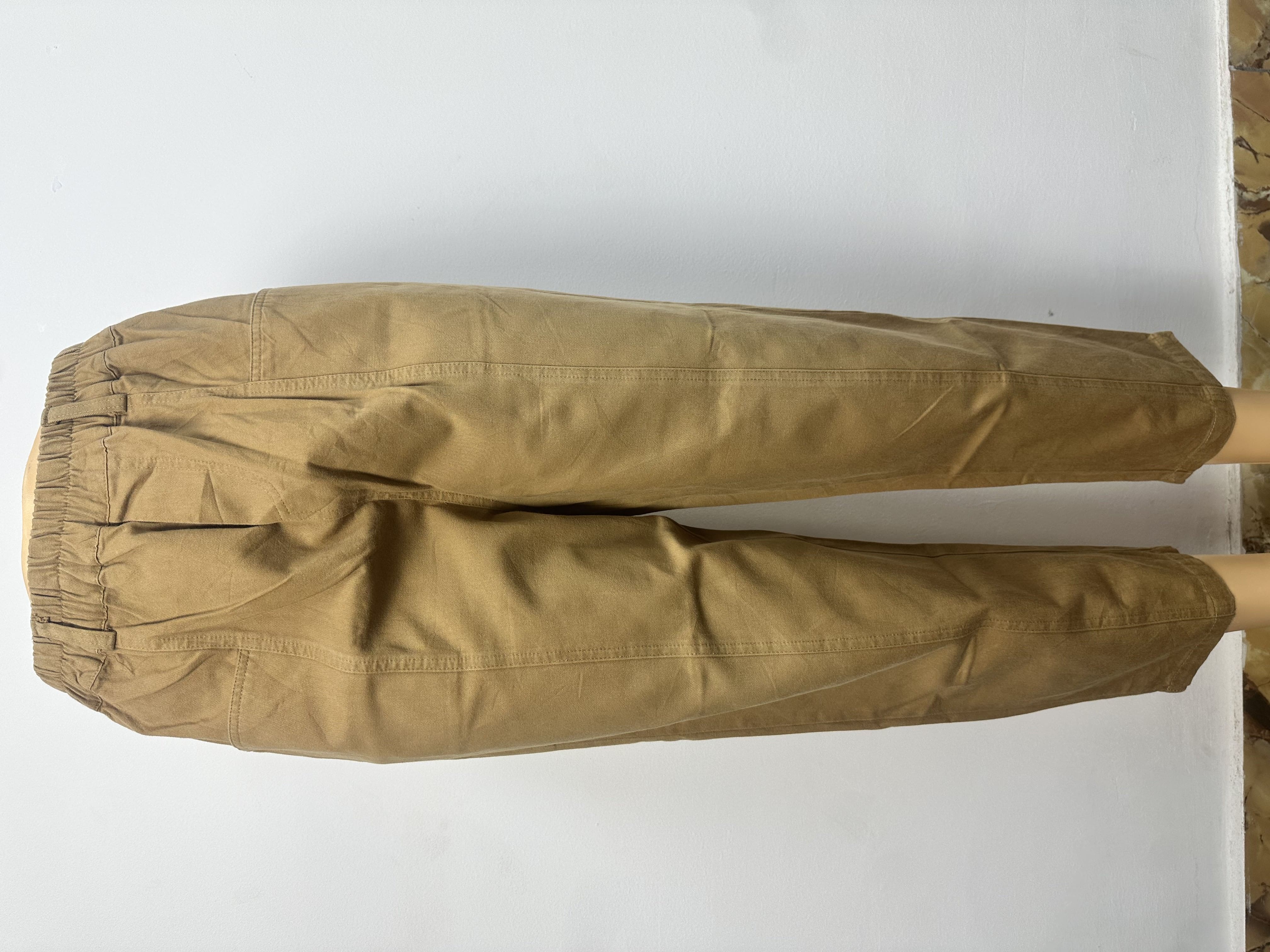 Pantalon, Ce pantalon est de couleur marron clair uni, avec une ceinture élastique sans boutons ni cordon de serrage visibles. Sa coupe est ample et droite, légèrement fuselée vers la cheville.