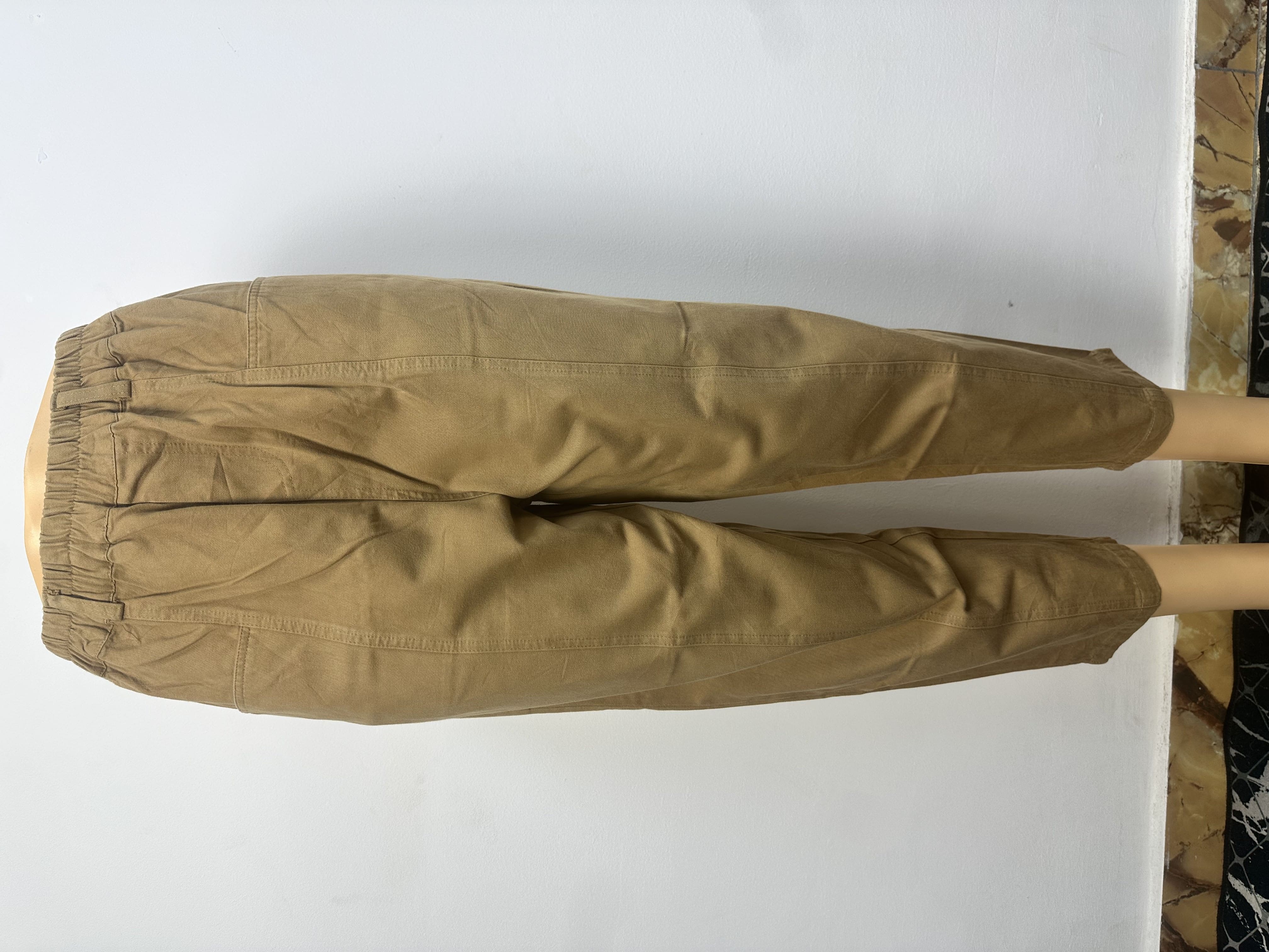 Pantalon, Ce pantalon est de couleur marron clair uni, avec une ceinture élastique sans boutons ni cordon de serrage visibles. Sa coupe est ample et droite, légèrement fuselée vers la cheville.