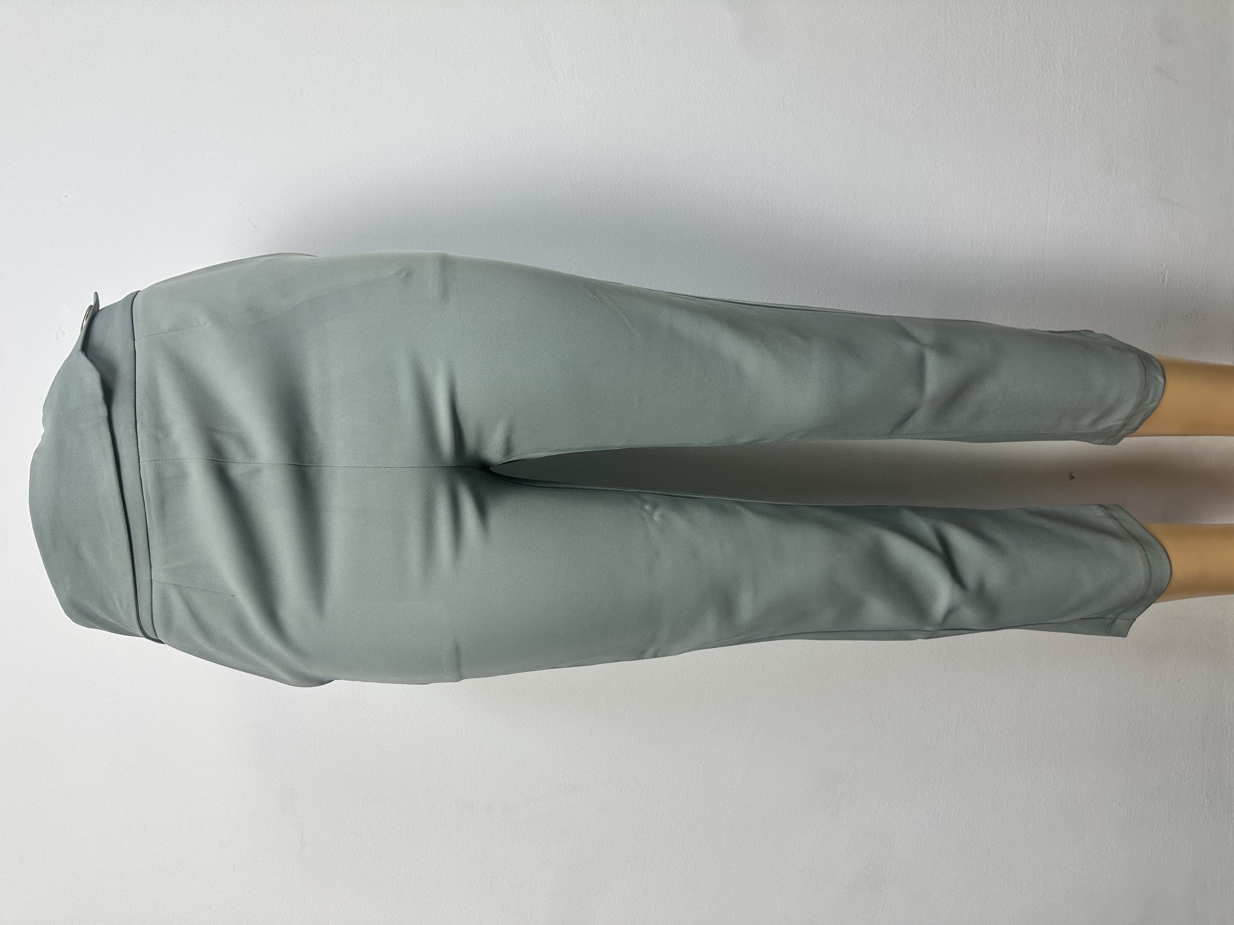 Pantalon est de couleur gris clair uni, à la texture lisse, avec une ceinture ajustée et une couture sur le devant de chaque jambe.
