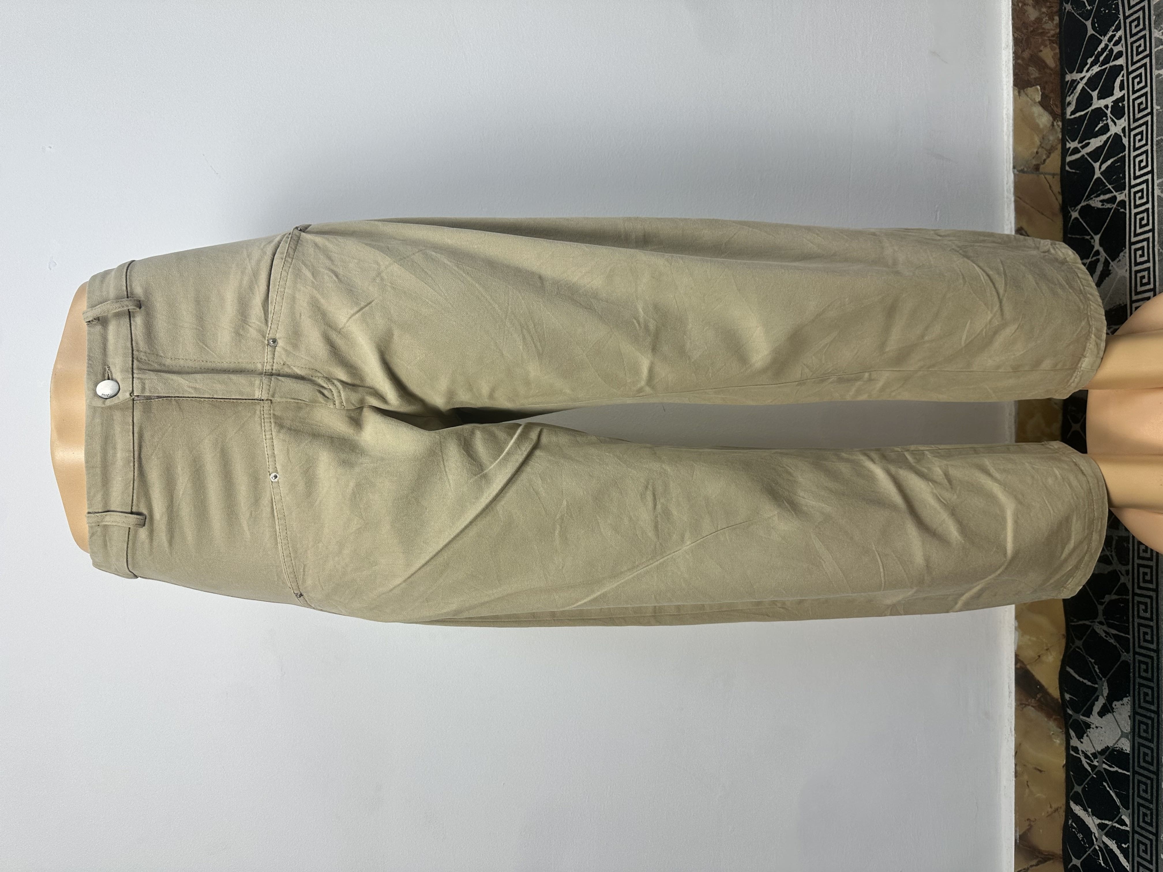 Pantalon beige kaki uni, avec une ceinture ajustée à passants et une fermeture boutonnée. La coupe est droite et ample, coupée au-dessus de la cheville.