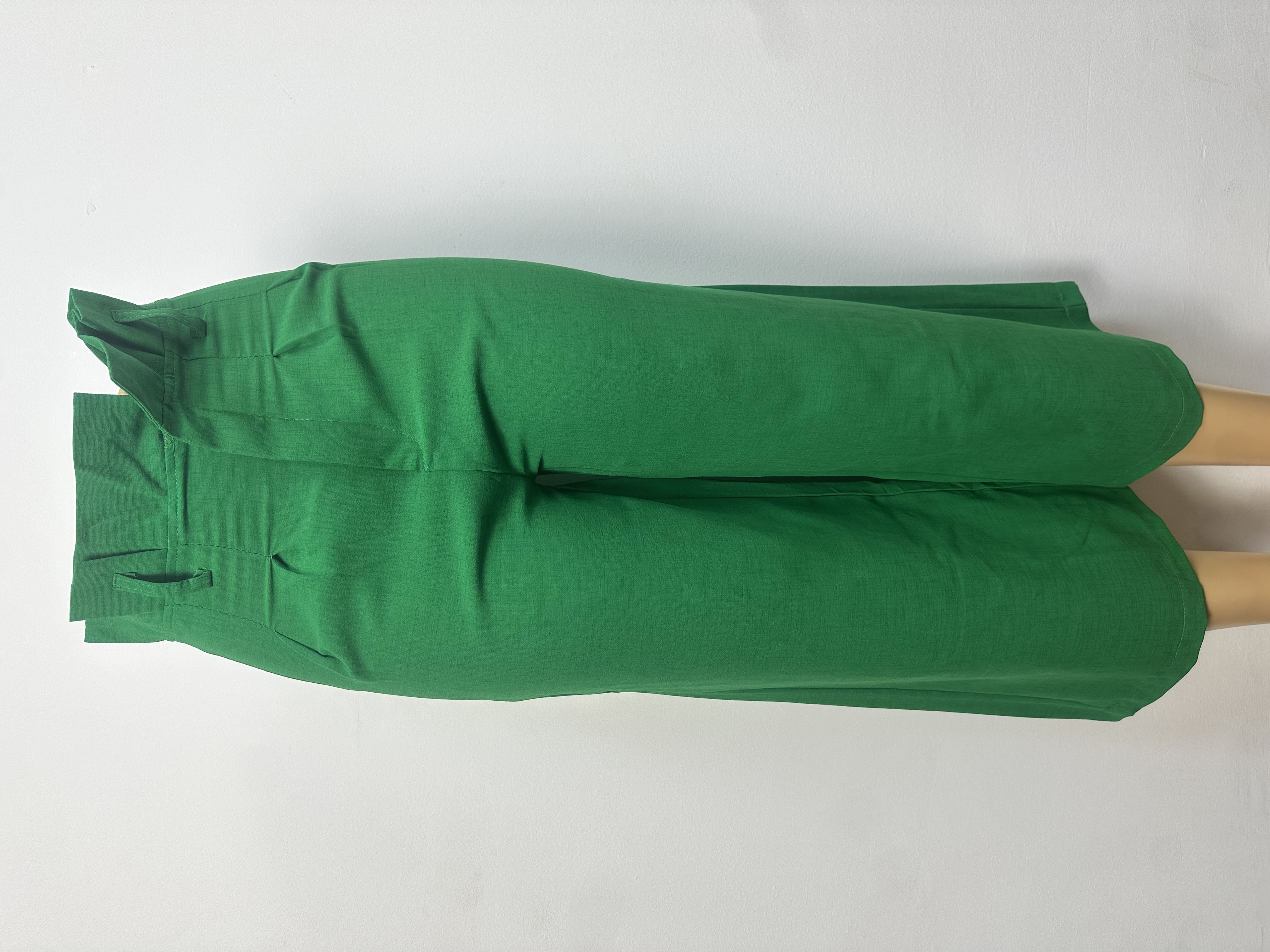 Pantalon vert vif uni, avec ceinture ajustée, passants et fermeture boutonnée. Coupe droite et courte au-dessus de la cheville.