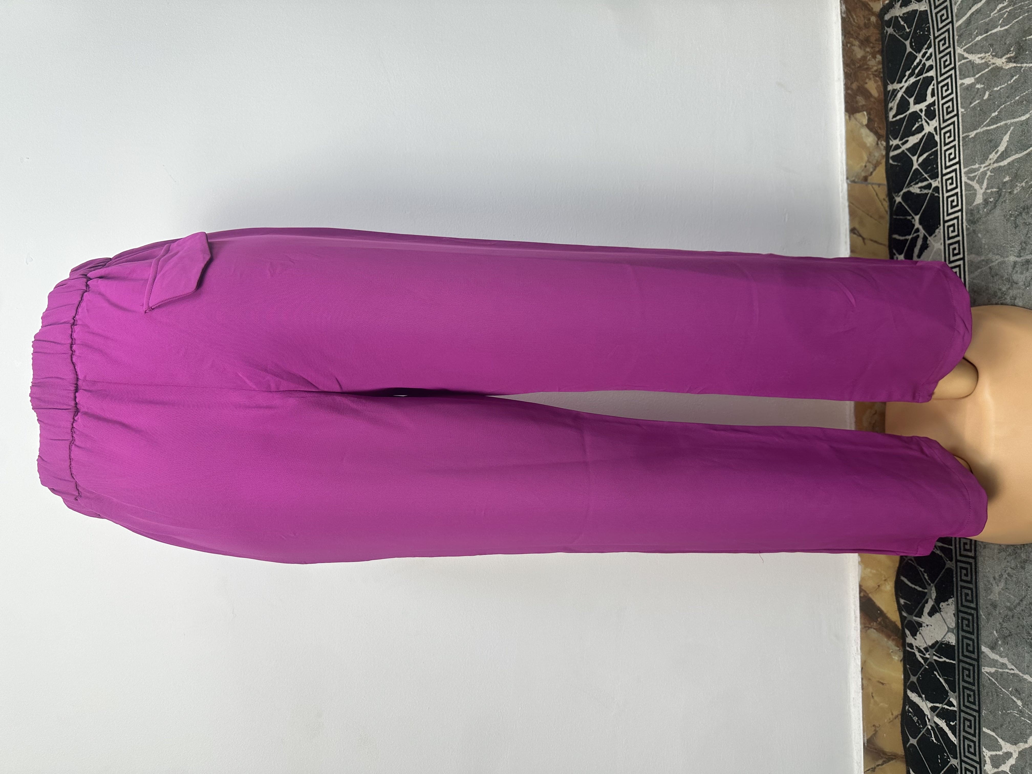 Le pantalon de couleur magenta uni, avec une taille ajustée, des passants, une fermeture à boutons et une petite étiquette blanche sur la ceinture gauche.
